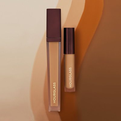 Liquid concealer with applicator on a beige background with a shop now button.