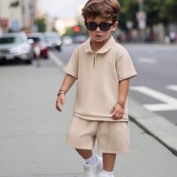trendy, casual-outfit A little boy wearing trendy casual beige co-ord set with t-shirt and shorts walking outdoors